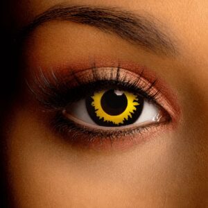 Close-up beauty shot of a brown eye wearing a Spooky Wolf Eye contact lens. The lens features a vivid yellow iris with jagged black wolf-like markings radiating inward around a dark pupil.