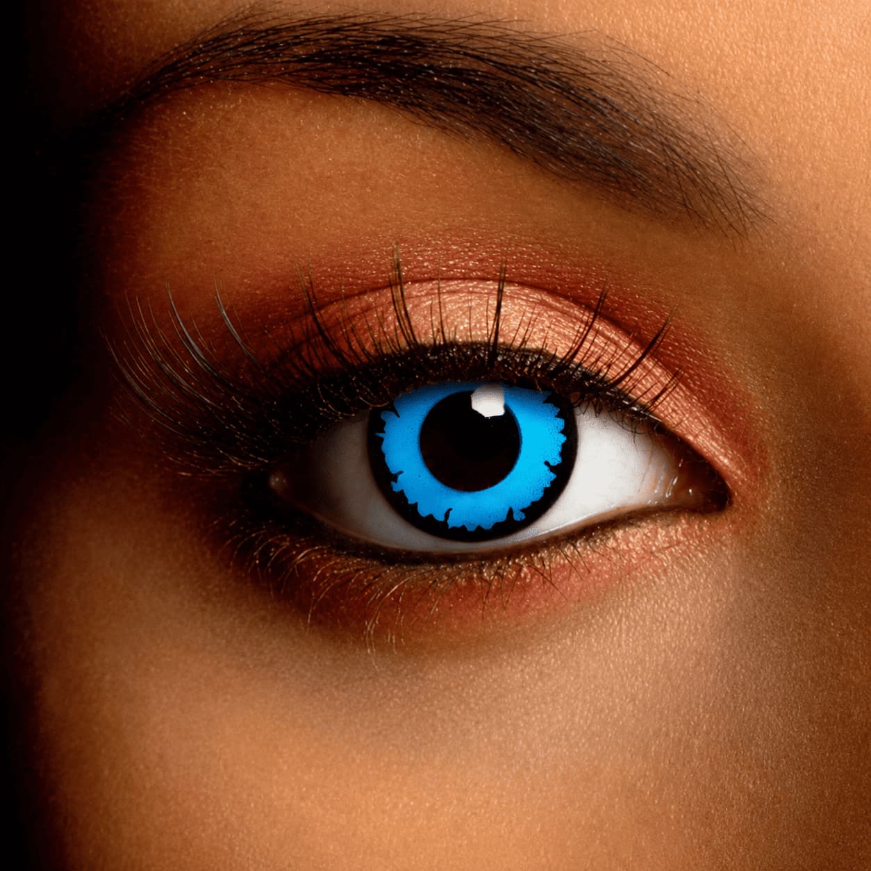Close-up of an eye wearing Wizard Blue Contact Lenses featuring a vivid electric blue iris with a jagged black ring design, creating a bold fantasy-inspired look.